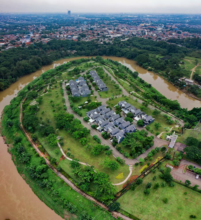 Aerial view of lush residential area surrounded by river in Sindang Jaya, Banten, Indonesia.