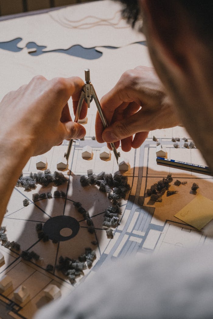 Architect using a compass for spatial planning on an architectural model indoors.